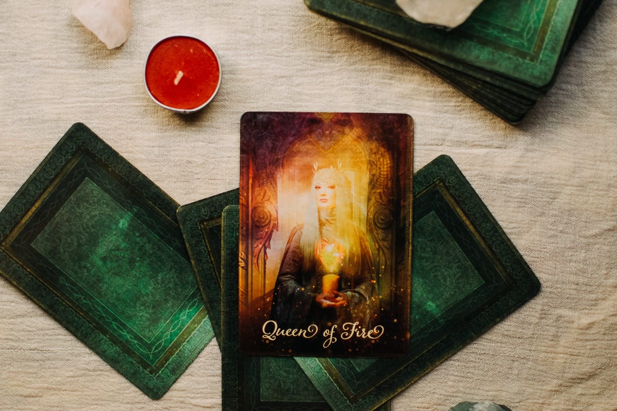 Queen of Fire (Wands) card surrounded by crystals and a candle. 