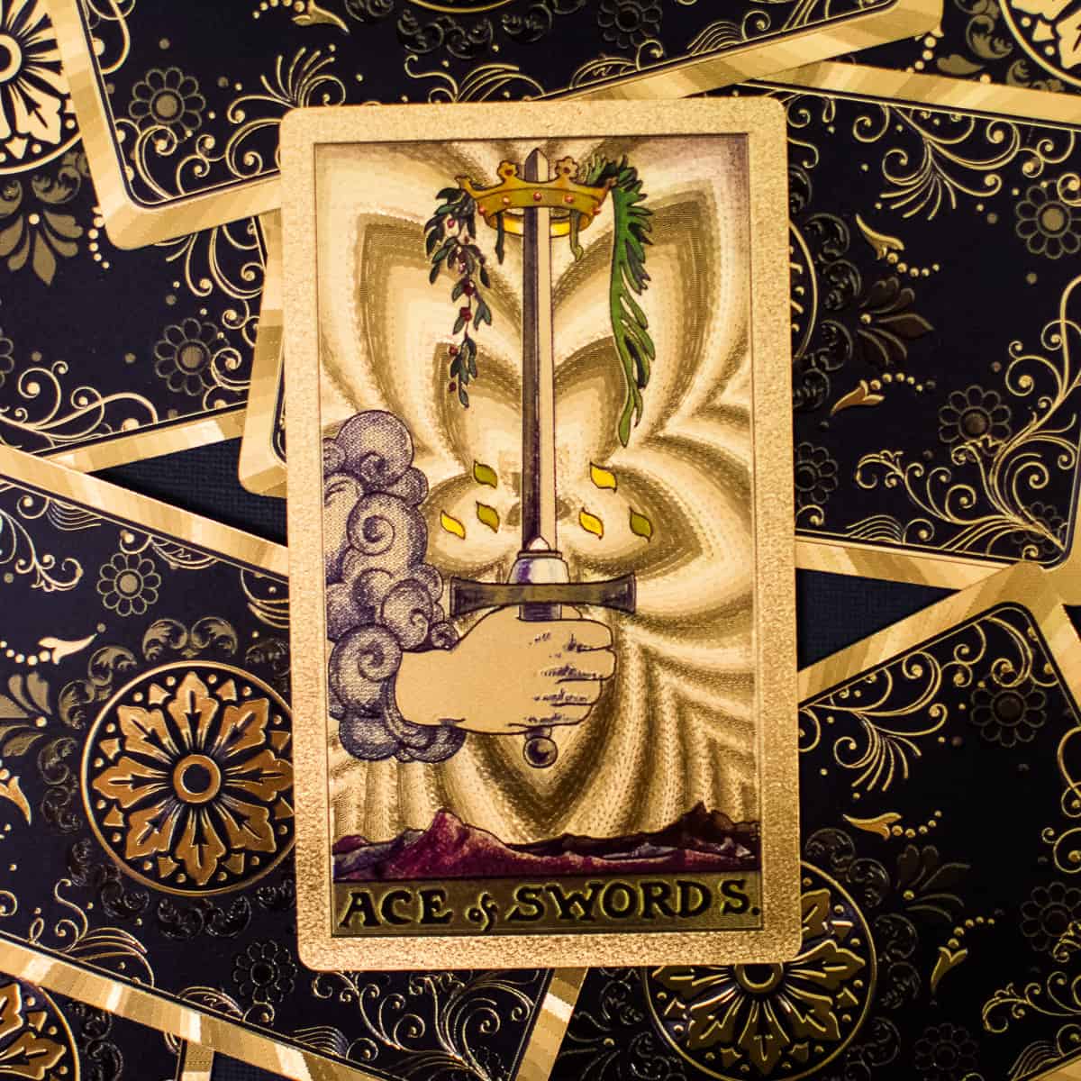 Hand emerging from clouds holding sword with crown on tarot card.