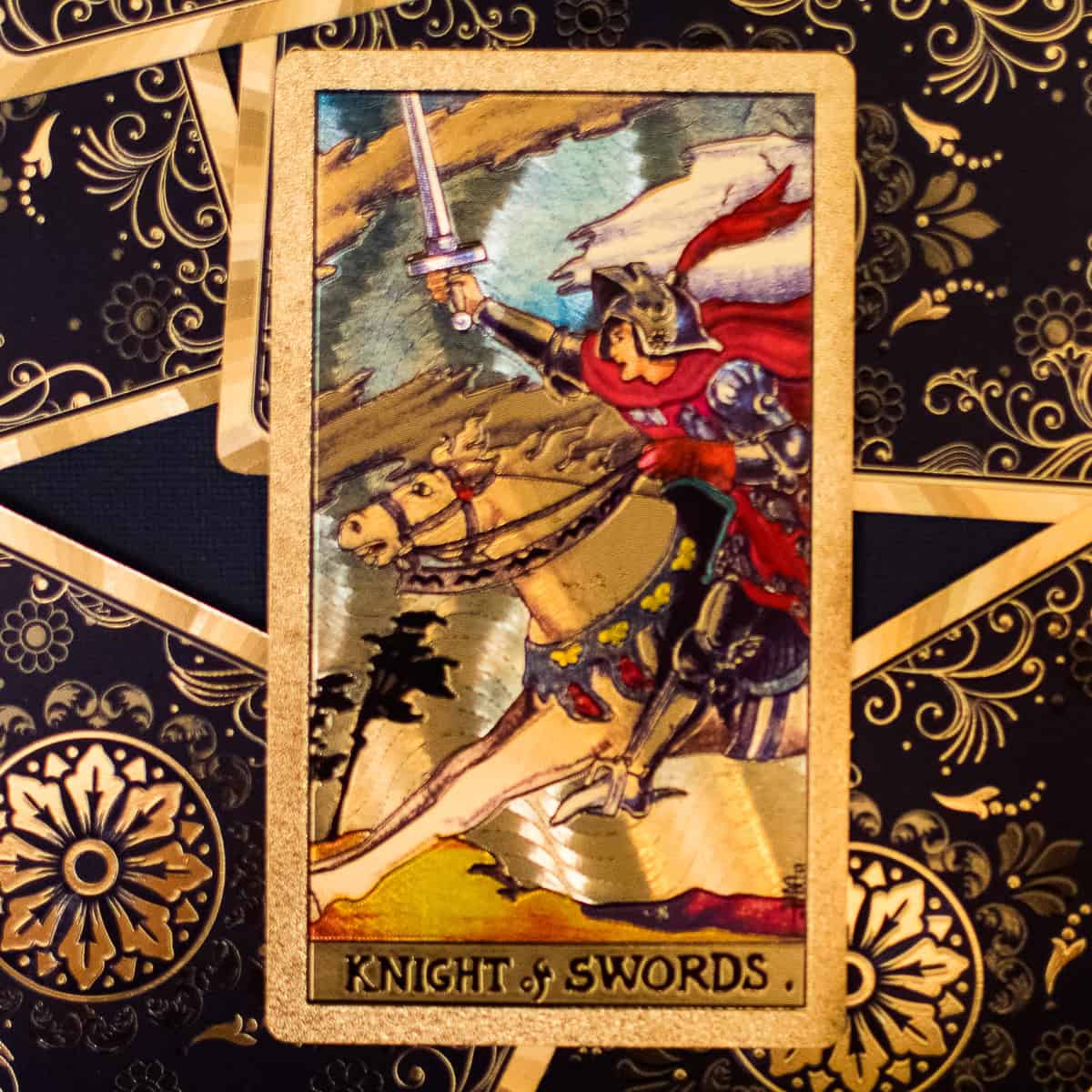 A knight charging on horse with sword drawn depicted on a tarot card. 