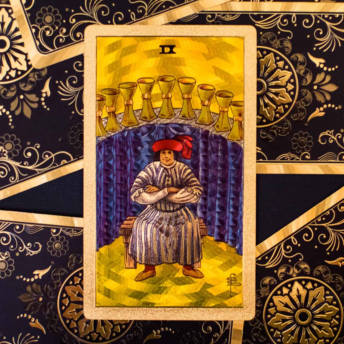 9 cups arched over a mans head depicted on a tarot card.