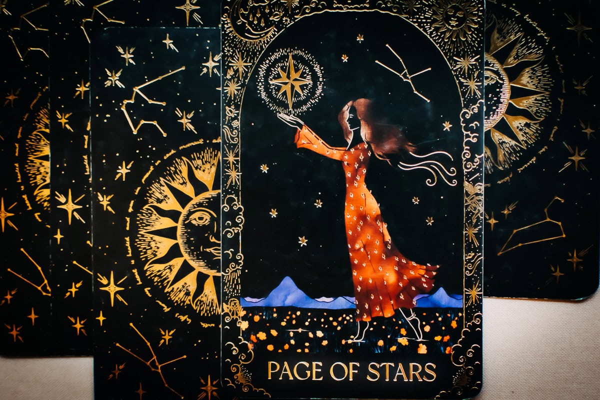 The Page of Stars (Pentacles) card showing a young woman with a whole pentacle in hand.