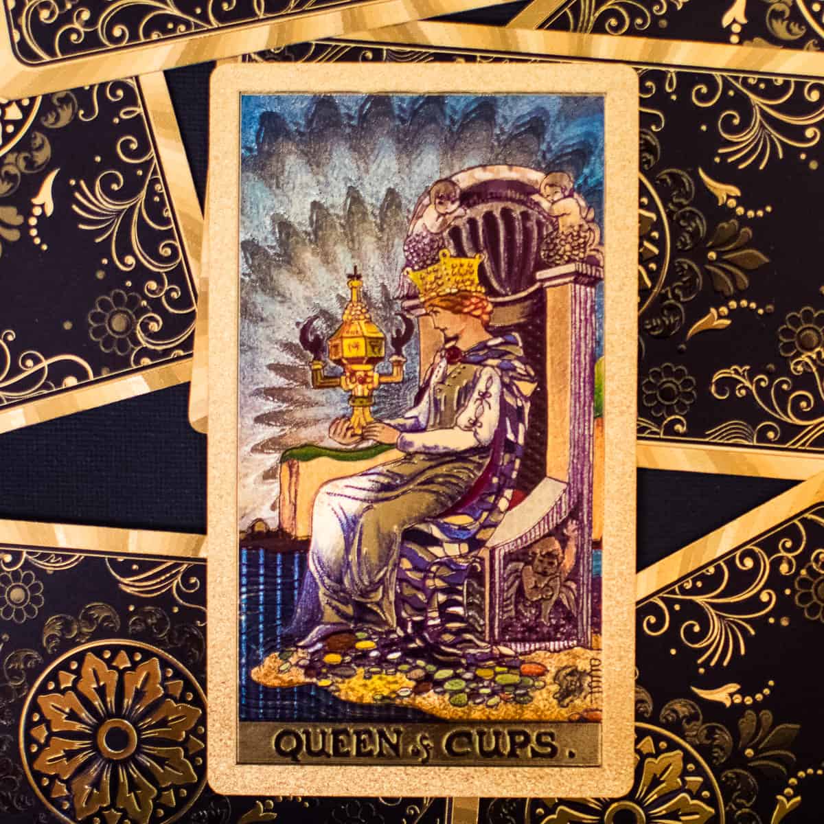 A queen on a throne with a golden cup, depicted on a tarot card.
