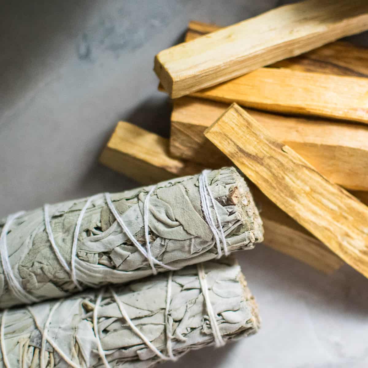 Bundles of sage and a stack of palo santo pieces.