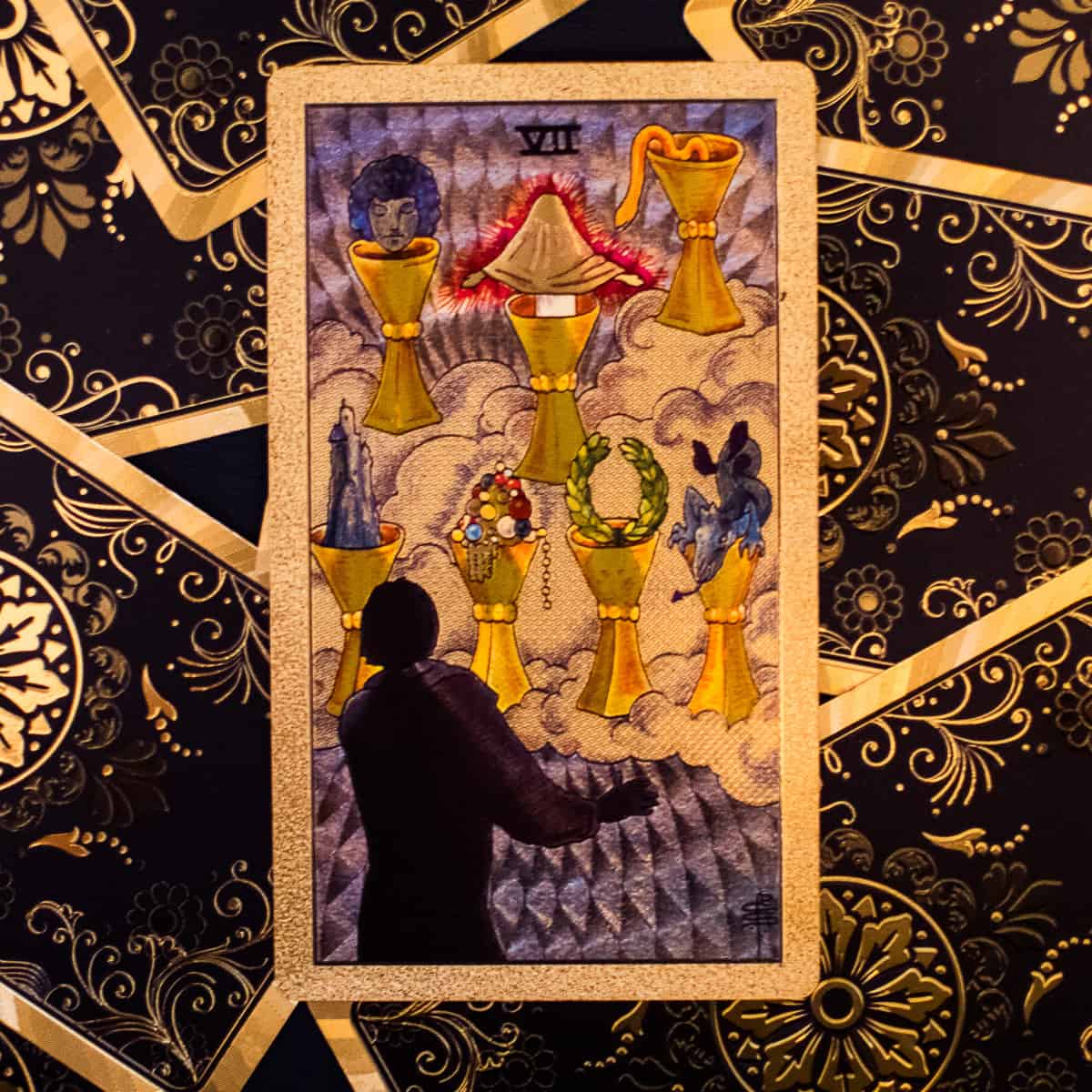 Seven various cups for choosing depicted on a tarot card.