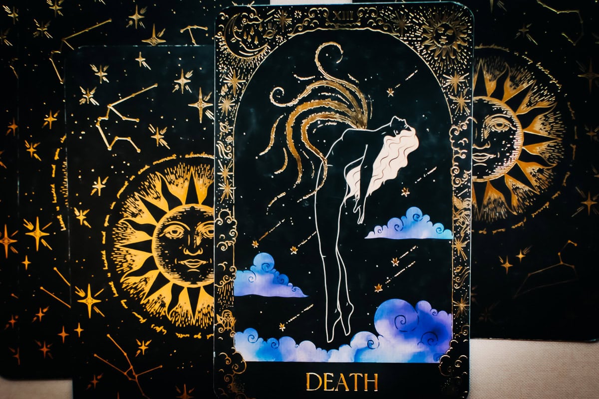 The Death card depicted by a woman going through an apparent transformative process among clouds.