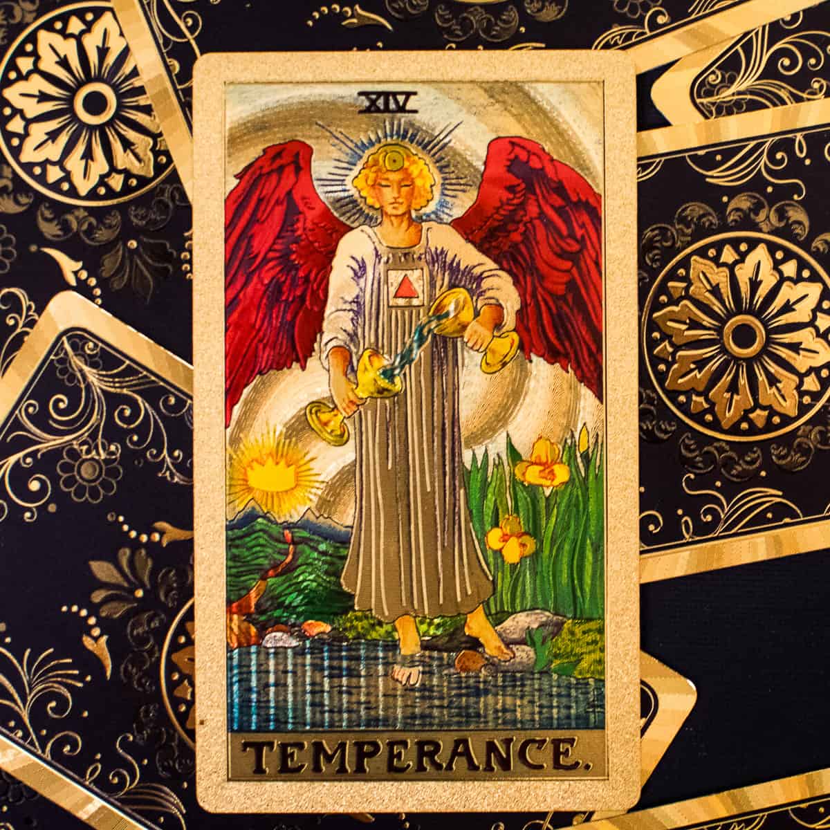 An angel standing with one foot on land and one foot in water depicted on a tarot card.
