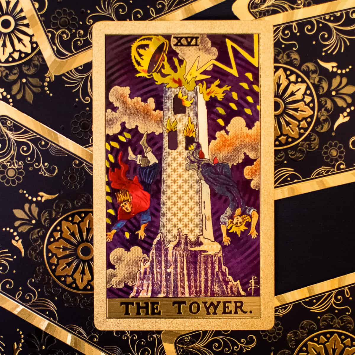 A tall tower being struck by lightening tumbling down in a storm depicted on a tarot card.