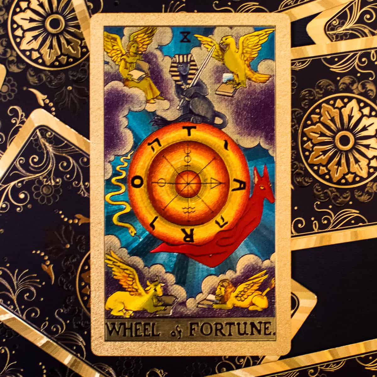 A wheel with all 4 zodiac symbols represented depicted on a tarot card.