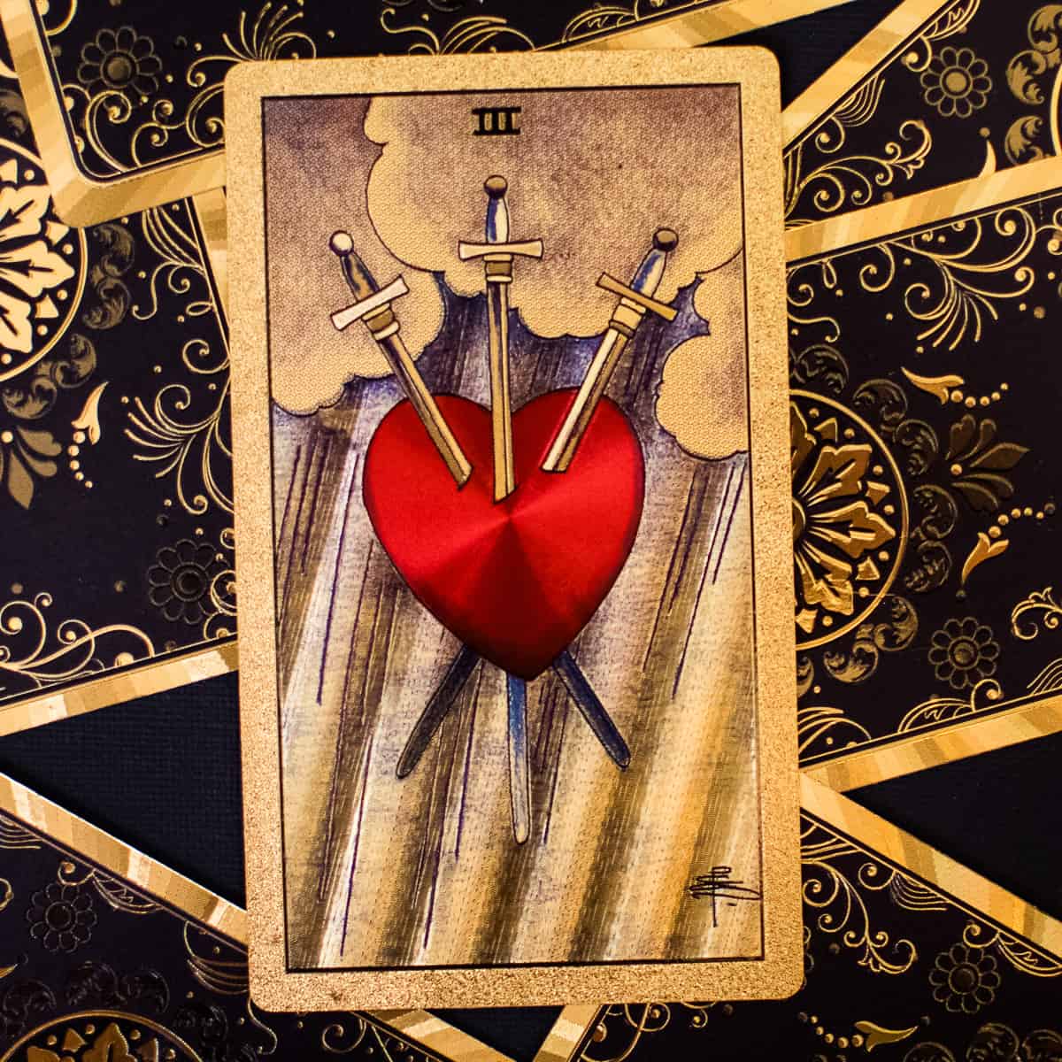 Three swords piercing a hart on a tarot card.
