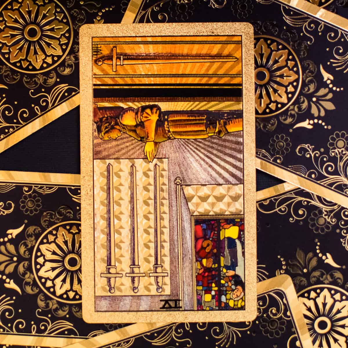 Four of Swords tarot card in the reversed position showing a man laying and resting with four swords hanging in the background.