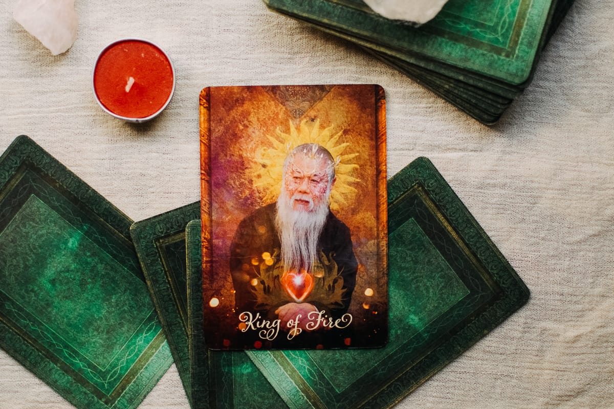 The King of Fire card surrounded by candles and a crystal. 