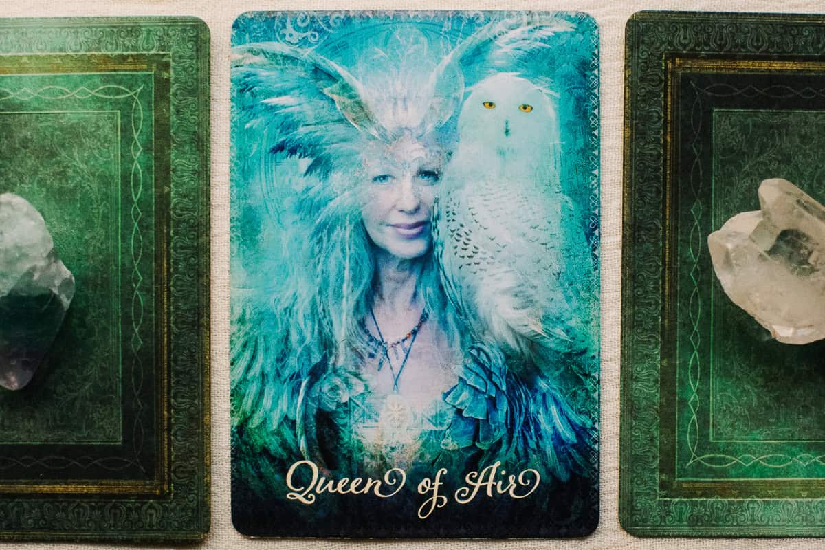 The Queen of Air (Swords) card depicted by a woman with a large white owl on her shoulder. 