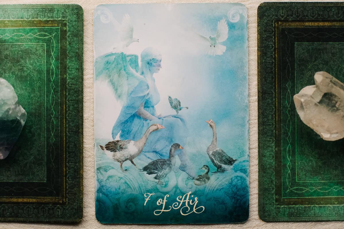 The Seven of Air (Swords) card depicting a woman surrounded by 7 birds. 