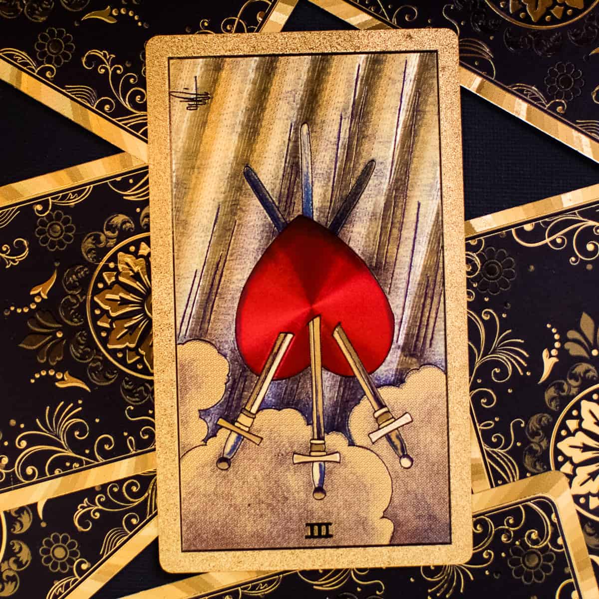 Three of Swords tarot card in the reverse position, depicting a heart with three swords pierced through it.