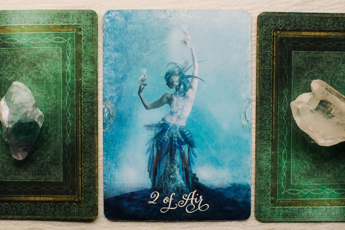 The Two of Air (Swords) person between two tarot cards. 